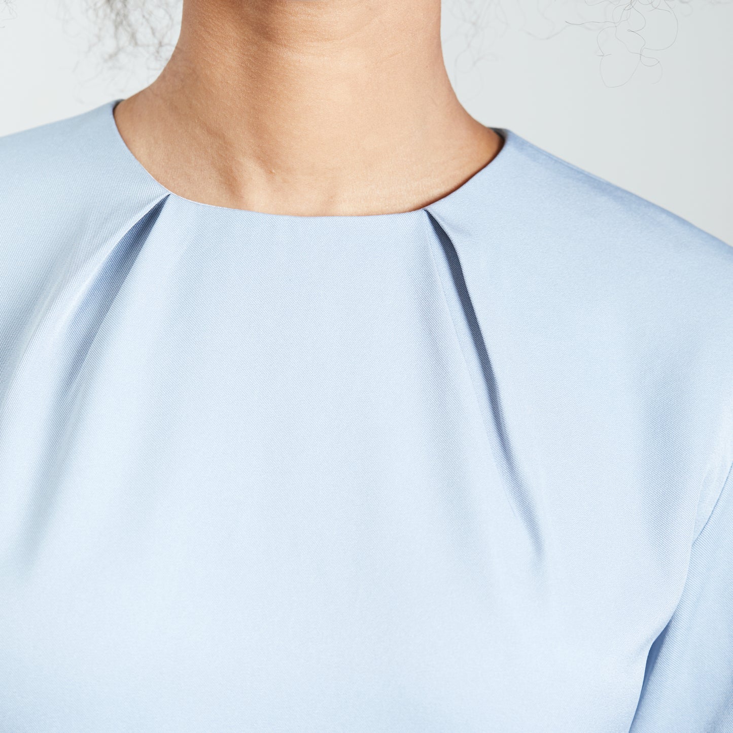 Detail view of the neck pleats on an ice blue dress